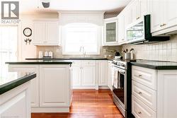 Kitchen featuring white cabinetry, dark countertops, a tile backsplash, and wood-finish flooring