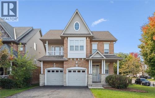View of front of house featuring a garage, driveway, brick siding, roof with shingles, and a porch