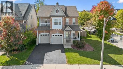Traditional-style home with driveway, a front yard, an attached garage, a porch, and brick siding