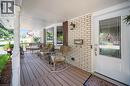 Inviting front porch featuring a white brick facade and wood-finish decking