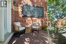 Outdoor balcony with dark composite decking, brick exterior wall, and a decorative geometric wall panel