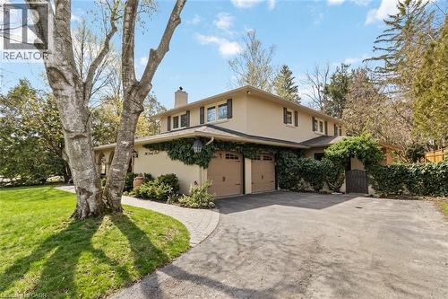 Stucco-finish exterior with dark brown trim accents, two attached garage doors, and established landscaping