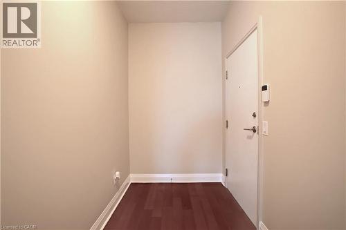 Entryway featuring rich wood-finish flooring, light neutral walls, white baseboards, and a solid core entry door with contemporary hardware