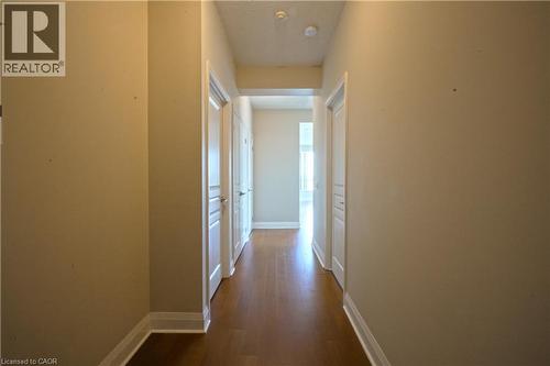 Hallway featuring wood-finish flooring, light neutral wall paint, and white paneled doors with chrome hardware