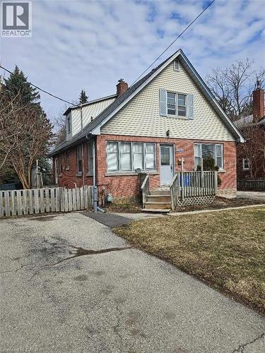 Brick and siding exterior featuring a gable roof, front porch with wood stairs, and a partial picket fence
