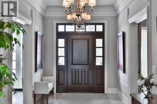 Entryway featuring a paneled wood door with frosted glass sidelights and transom, chandelier lighting, crown molding, and light-toned flooring