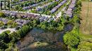 Residential neighborhood with diverse architectural styles, mature trees, and a prominent pond feature