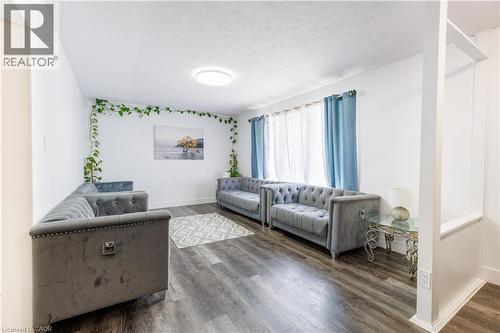 Spacious living area featuring wood-finish flooring, white walls, and a large window with sheers