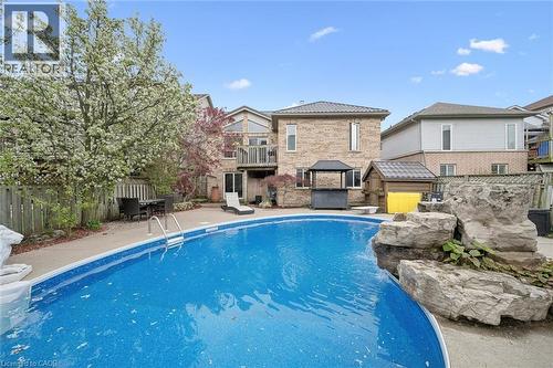 Expansive backyard featuring an inground swimming pool, surrounding concrete patio, and a rock waterfall feature