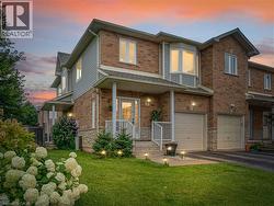 Brick and siding exterior featuring an integrated garage, covered front porch, a bay window, and a manicured lawn with established landscaping