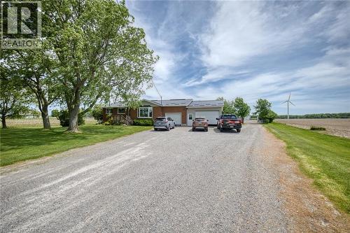 Brick exterior residence featuring a gravel driveway, mature trees, a two-car garage, and a bay window