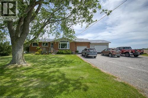 Brick-clad home featuring a bay window, covered porch entry, and a gravel driveway