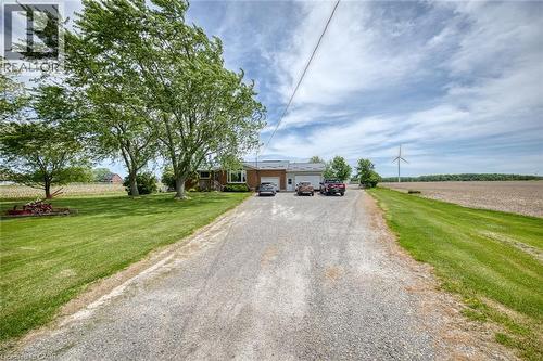 Expansive gravel driveway leading to a brick-front residence with an attached garage