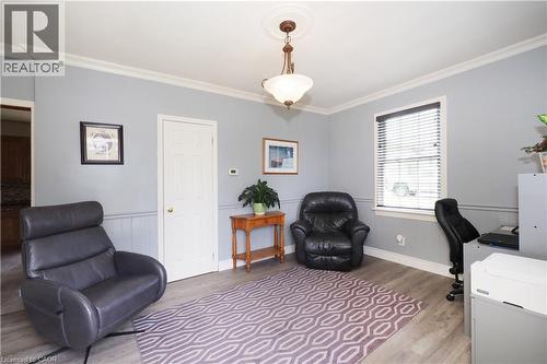 Spacious room featuring light gray walls with wainscoting, wood-finish flooring, a white paneled door, and a prominent window with blinds
