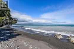 Sandy and pebble beach with a tranquil water body under a blue sky