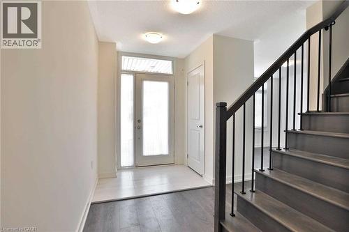 Entry foyer with wood-finish flooring extending to a matching staircase featuring black metal balusters