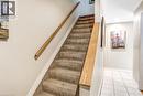 Carpeted staircase with light wood railings and neutral painted walls