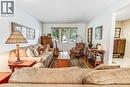 Bright living area with wood-finish flooring, a large window, white walls, and a decorative area rug