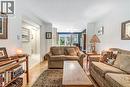 Bright living space featuring wood-finish flooring, white walls, and a hallway with tiled flooring