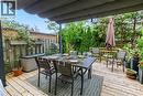 Expansive wood-finish deck with a retractable awning, surrounded by mature privacy plantings and a slatted wood fence with lattice detailing