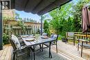 Spacious outdoor eating area featuring a retractable awning, natural wood decking, and privacy fencing with integrated planters