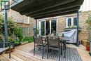 Wood-finish deck with a retractable awning and stone exterior