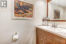Bathroom vanity featuring a wood-finish cabinet, white countertop with integrated sink, brushed nickel faucet, and a framed mirror