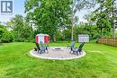 Community area, spacious backyard featuring a central fire pit area with stone paver edging, storage shed with community garden tools, mature trees, and a wood privacy fence