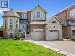 Stone and brick facade residence featuring a two-car garage, turret architectural element, and a stone retaining wall