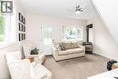 Living area featuring a floor-to-ceiling fireplace, bay window, white trim, and a ceiling fan with integrated lighting
