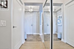 Hallway featuring wood-finish flooring transitioning to stone tile, a tray ceiling with a chandelier, and a mirrored closet