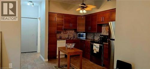 Kitchen featuring wood-finish cabinetry, patterned tile backsplash, and dark countertops