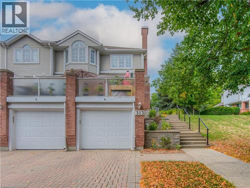 Brick and siding exterior featuring two attached garage doors, a second-story bay window, and a glass-paneled balcony