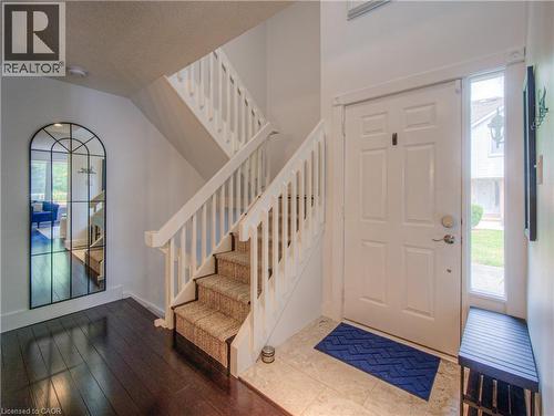 Entryway featuring a paneled door with sidelight, wood-finish flooring, and a carpeted staircase with white balusters