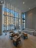 Spacious common area featuring full-height windows, decorative suspended ceiling elements, recessed lighting, and vertical slatted wall paneling