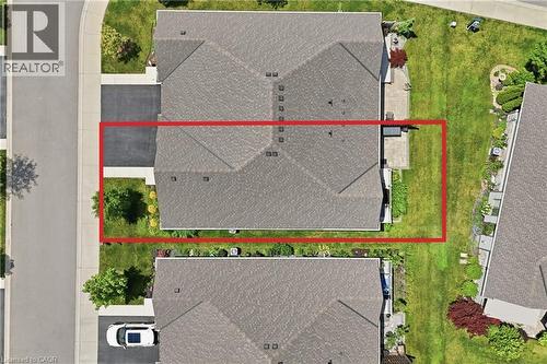 Aerial view showcasing a property with a gray shingle roof, a paved driveway, and a concrete pathway