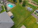 Expansive rear yard featuring a freeform swimming pool with rock features, a paved patio, a wooden deck, and two storage sheds