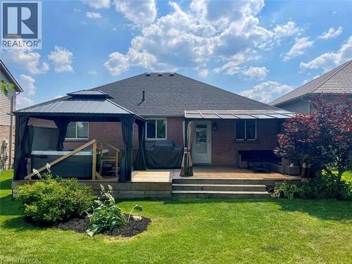 Expansive backyard featuring a multi-level wooden deck with steps, an integrated pergola providing shade, and a dedicated covered area housing a hot tub