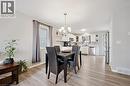Dining area featuring wood-finish flooring, a contemporary chandelier, and a window with privacy glass