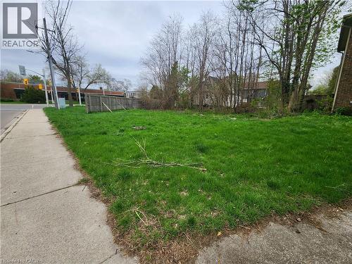 Expansive grass lot featuring mature perimeter trees and a sidewalk border