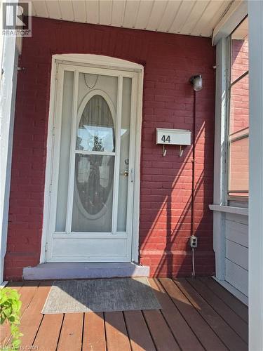 Red brick facade with a white storm door featuring an oval glass insert
