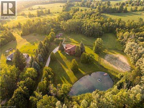 Expansive property featuring a private pond with a fountain and dock, extensive landscaping with mature trees, a long gravel driveway, and a residential structure