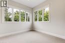 Dedicated room featuring multiple large windows, flush-mount lighting, and light-toned wall paint AI staged