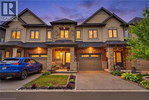 Modern townhome exterior featuring stone and brick accents, a gabled roofline, an attached garage, a covered front entry, and a paved driveway