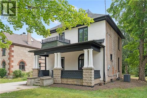 Stucco and stone exterior with a covered porch featuring decorative pillars and a second-story balcony with wrought iron railing