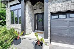 Stone facade entrance featuring a dark wood-paneled door with transom window, modern black-framed windows, and an integrated garage with upper window panels