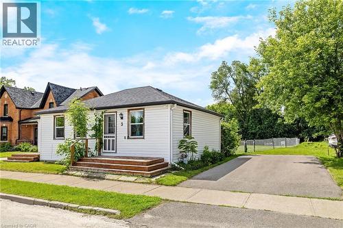 White siding exterior with dark trim windows, multi-tiered wood deck, asphalt driveway, and mature landscaping