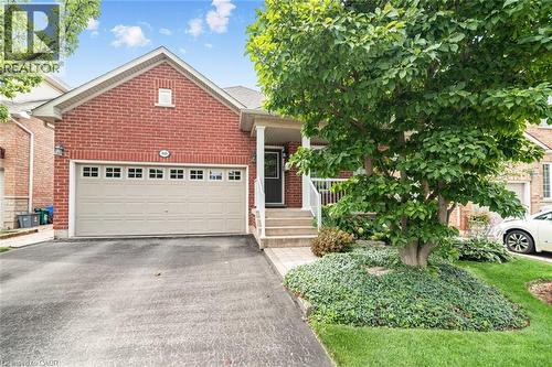 Brick exterior with an attached garage, paved driveway, and a covered front entry