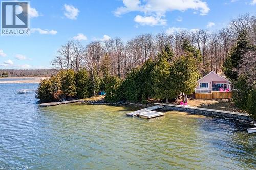 Waterfront property featuring a private dock, expansive deck, mature trees, and direct water access