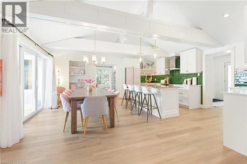 Open-concept living space featuring wood-finish flooring, vaulted ceilings with exposed beams, and sliding glass doors